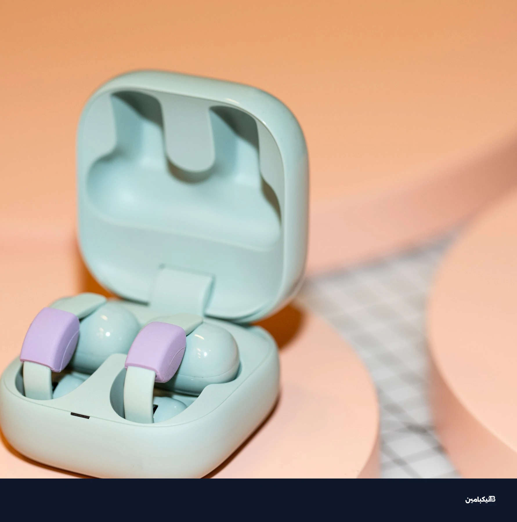 Sony LinkBuds Clip in their open case on a peach surface.