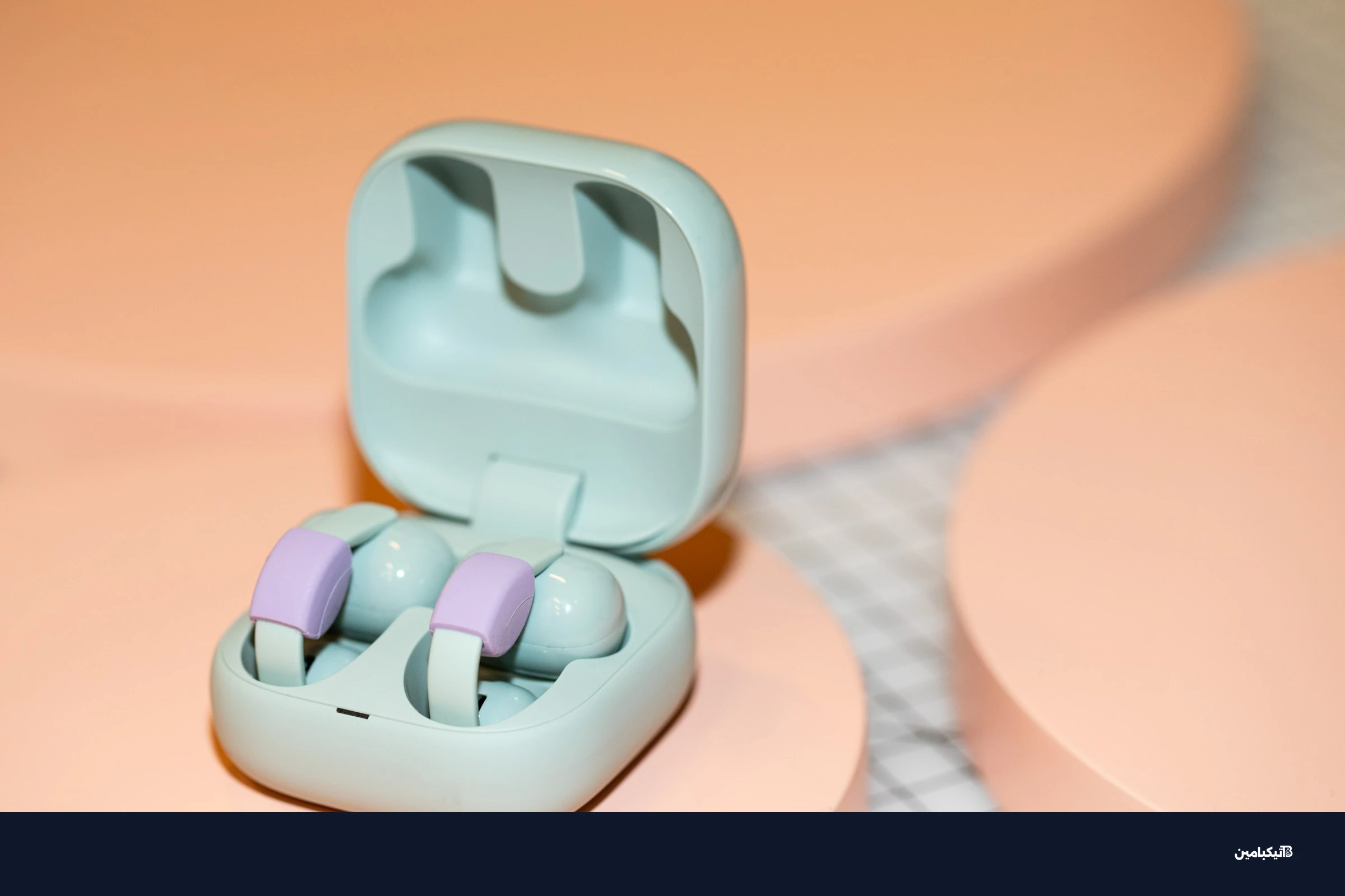 Sony LinkBuds Clip in their open case on a peach surface.