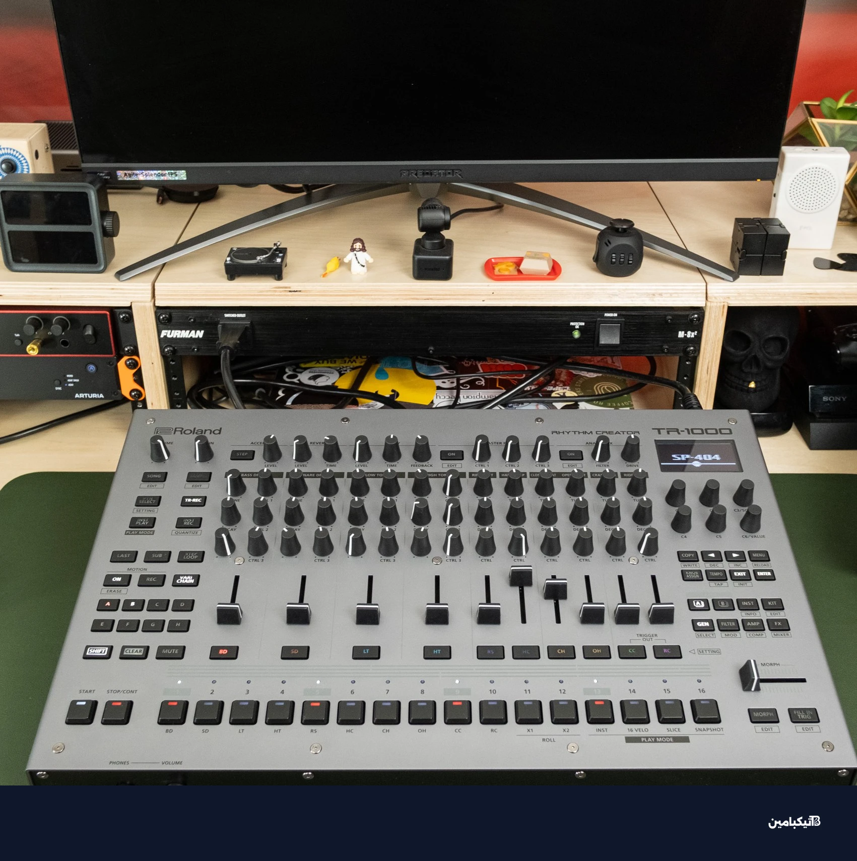 صورة واسعة لجهاز رولاند TR-1000 على مكتب بجانب معدات موسيقية أخرى