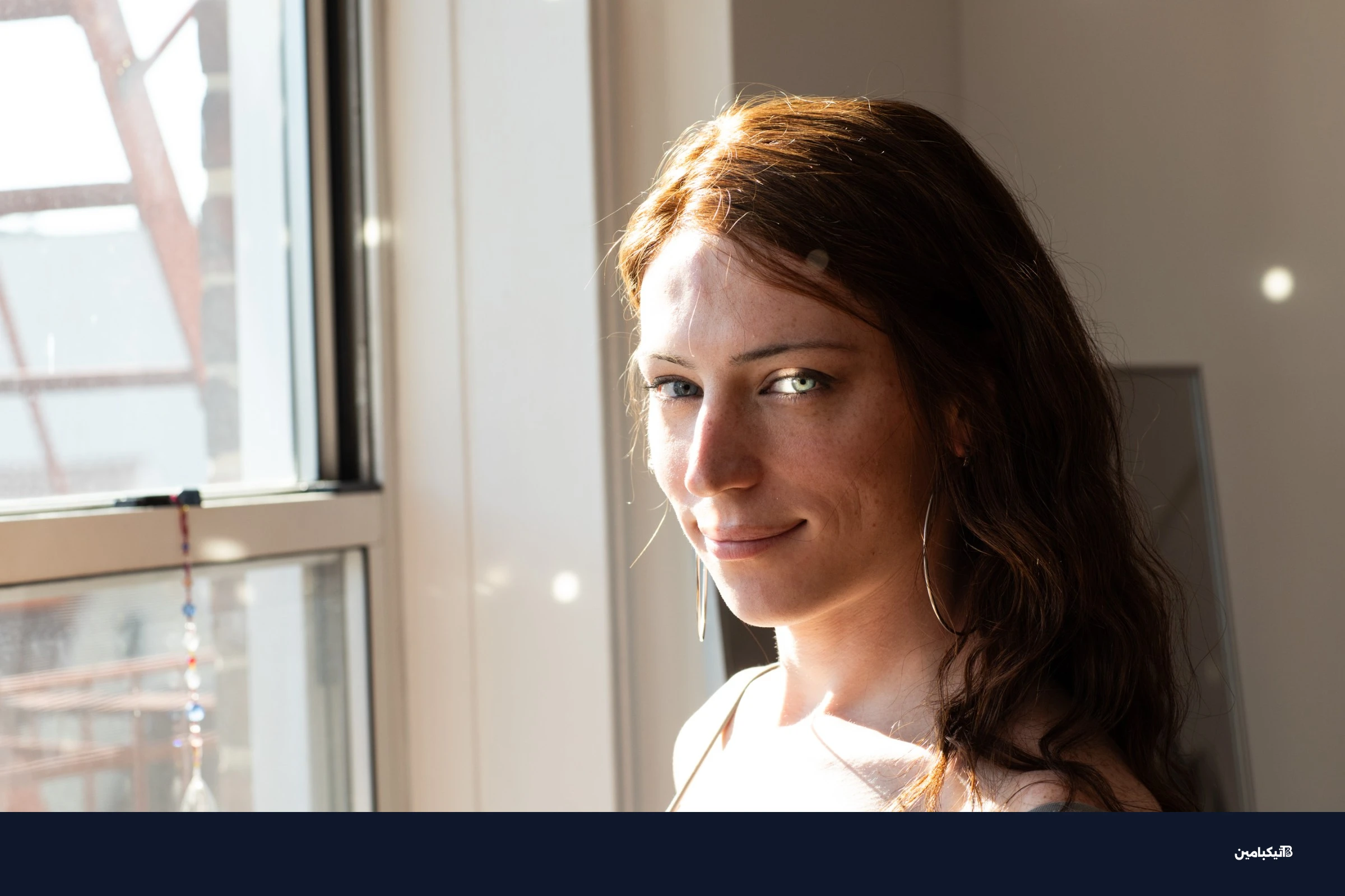 بري أودونيل تجلس بجانب نافذة غرفة نومها وتنظر إلى الكاميرا، بينما ينعكس ضوء الشمس عبر طيف يقفز بأقراص صغيرة من الضوء على وجهها والجدار خلفها