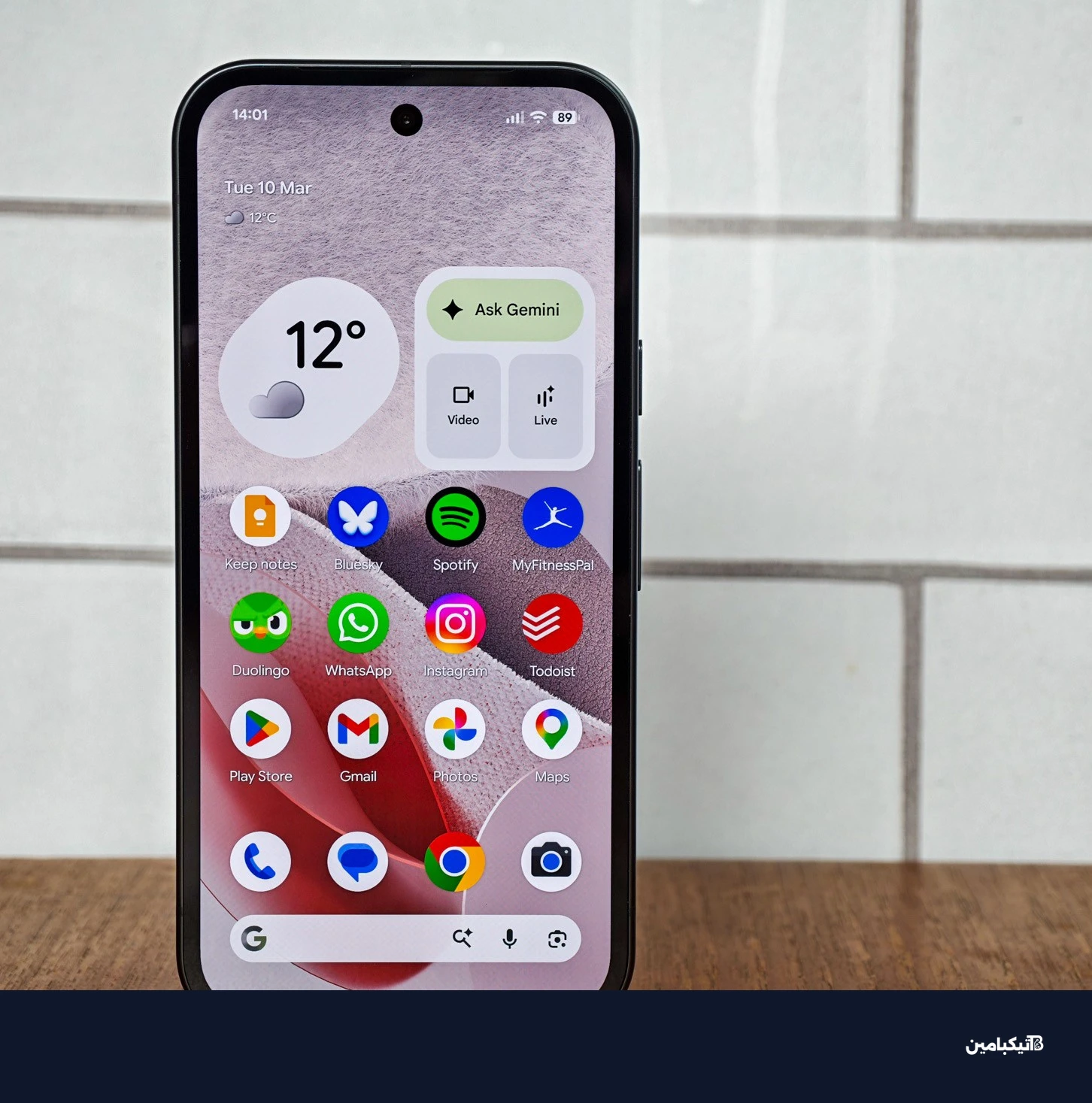 صورة جوجل Pixel 10A أمام بلاط أبيض، تعرض شاشة الرئيسية