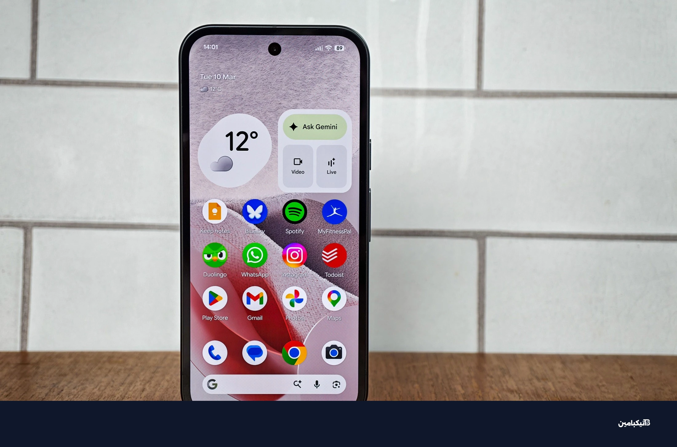 صورة جوجل Pixel 10A أمام بلاط أبيض، تعرض شاشة الرئيسية